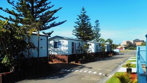 Fileira de casas móveis, com uma estrada pavimentada e vegetação ao primeiro plano.