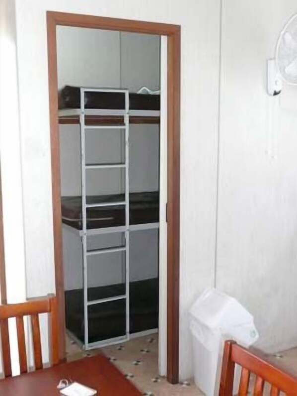 Una habitación con literas, una mesita y una silla.