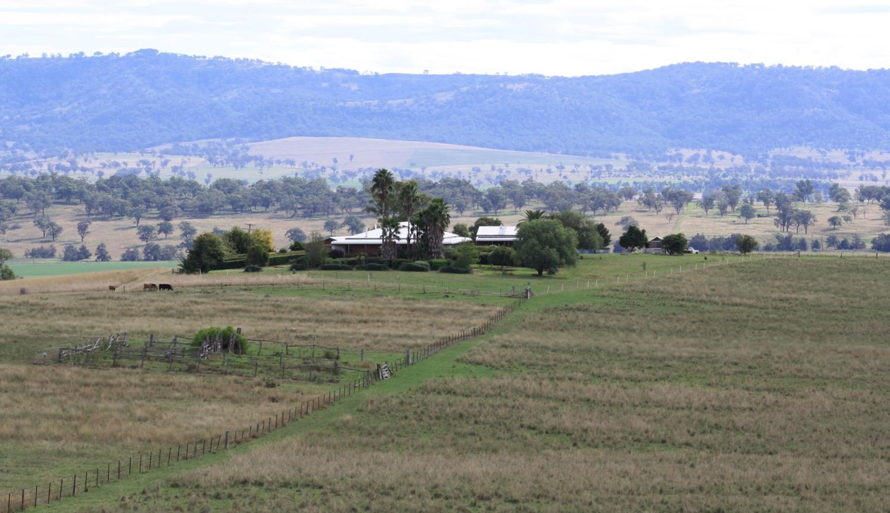 Un paisaje rural con una casa grande rodeada de campos y árboles.