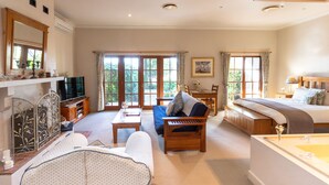 A spacious living room with a sofa, a coffee table, a TV, and a dining area with a table and chairs. - Strathearn Park Lodge (Scone)