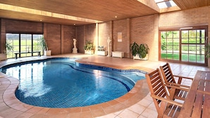 An indoor swimming pool with tiled flooring, wooden benches, and potted plants. - Strathearn Park Lodge (Scone)