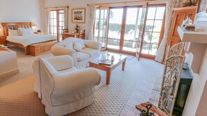 A spacious bedroom with a large bed, a sofa, a coffee table, and a view through the large windows. - Strathearn Park Lodge (Scone)