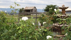 A rustic wooden structure with a metal roof, surrounded by lush greenery and a stone fountain. - Strathearn Park Lodge (Scone)