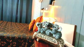 A bed with a patterned bedspread, a 'Welcome' sign, and a lamp.