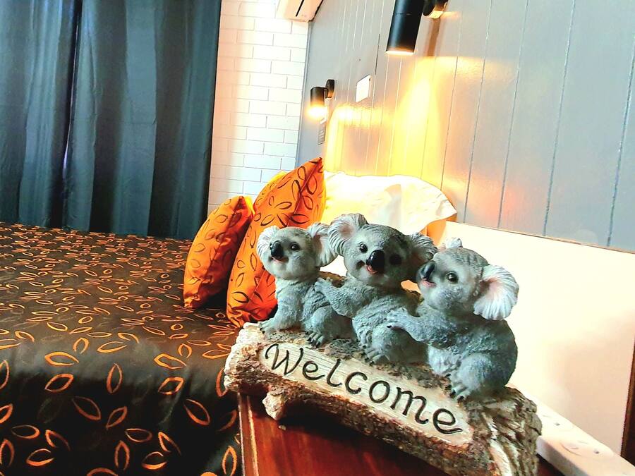 A bed with a patterned bedspread, a 'Welcome' sign, and a lamp.