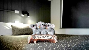 A bed with a patterned bedspread and a decorative welcome sign with koalas. - Young Goldrush Motel (Young)
