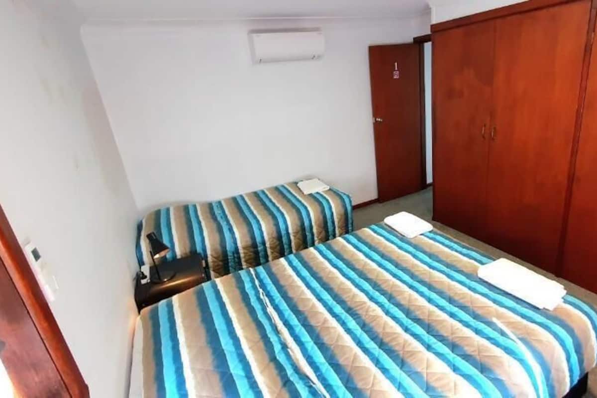 Una habitación con dos camas, un armario y una puerta.