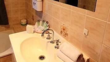 Un baño con lavamanos, espejo y artículos de aseo.