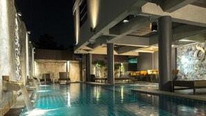 Une piscine avec un mur en pierre et des chaises longues.