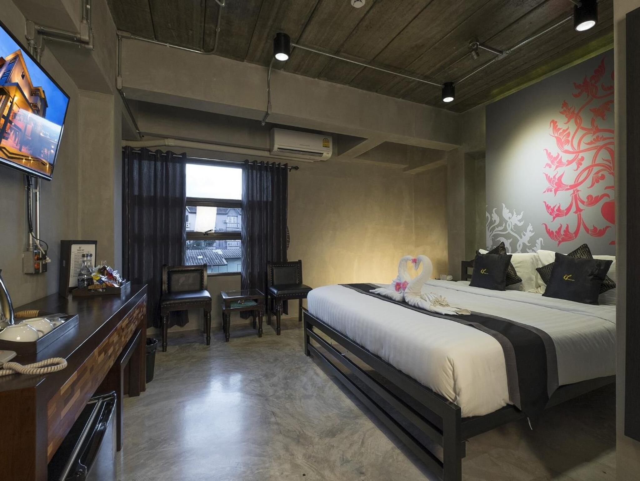 A hotel room with a bed, a desk, a television, and a window with curtains.