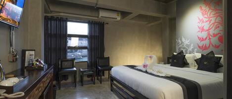 A hotel room with a bed, a desk, a television, and a window with curtains.