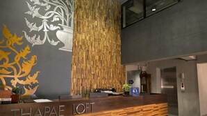 Un comptoir d’accueil au design en bois, orné d’un logo, un panneau vertical en bois et un ascenseur.