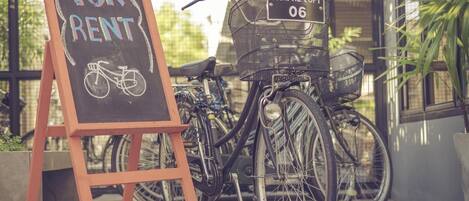A bicycle with a basket and a sign that says "FOR RENT" on a chalkboard.