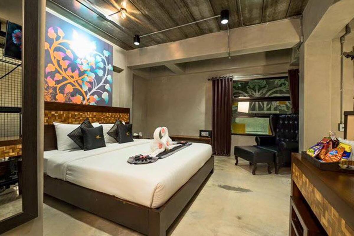 A modern hotel room with a large bed, a desk, and a view of the outdoors.