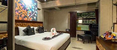 A modern hotel room with a large bed, a desk, and a view of the outdoors.