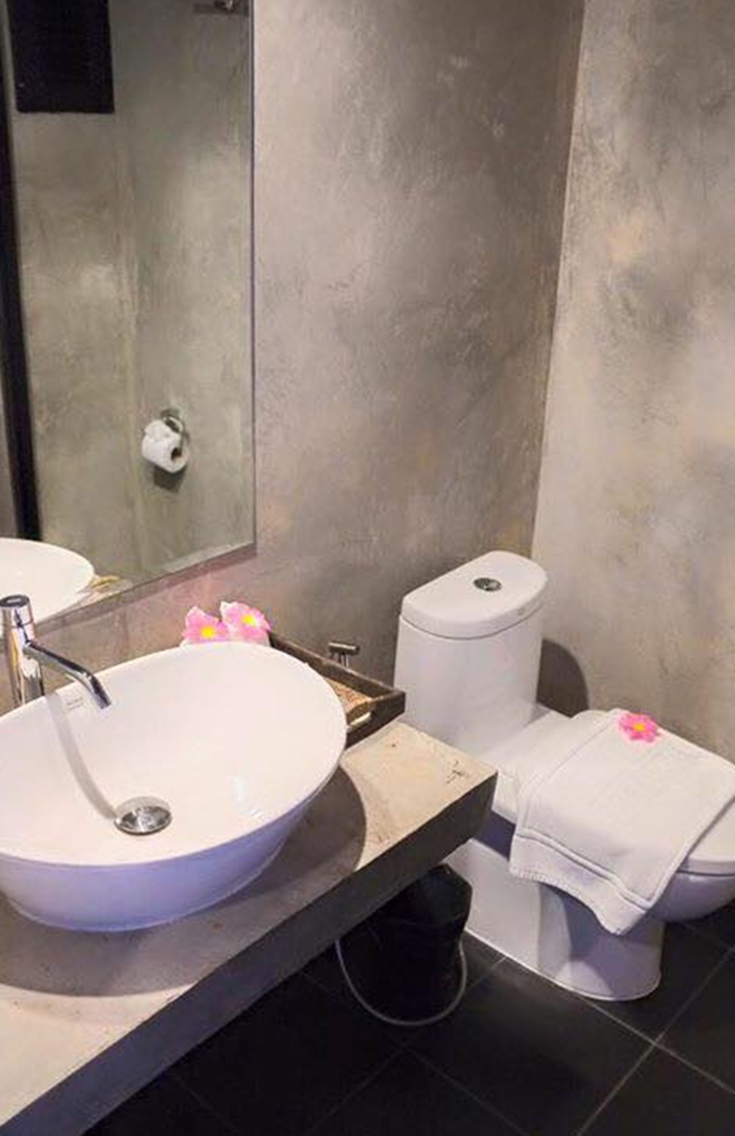 A bathroom with a white sink, a toilet, and a mirror.