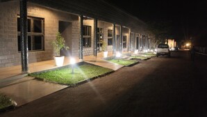 A building with a brick facade, multiple windows, and a paved entrance area with planters. - Mika Convention Center Meanwood (Lusaka)