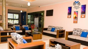A modern hotel lobby with sofas, coffee tables, and a large window. - Mika Convention Center Meanwood (Lusaka)