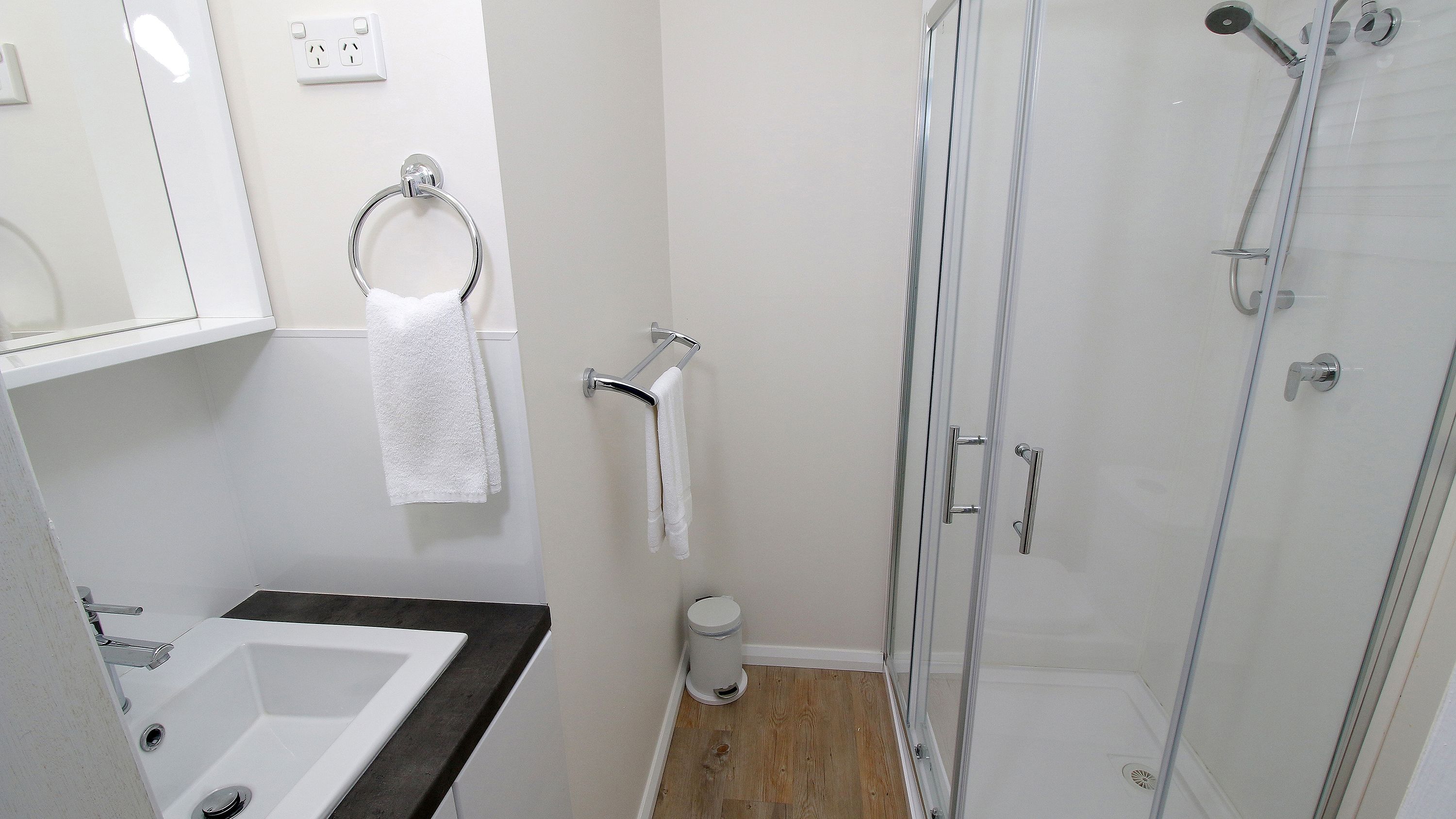 A bathroom with a sink, towel rack, toilet, and shower.