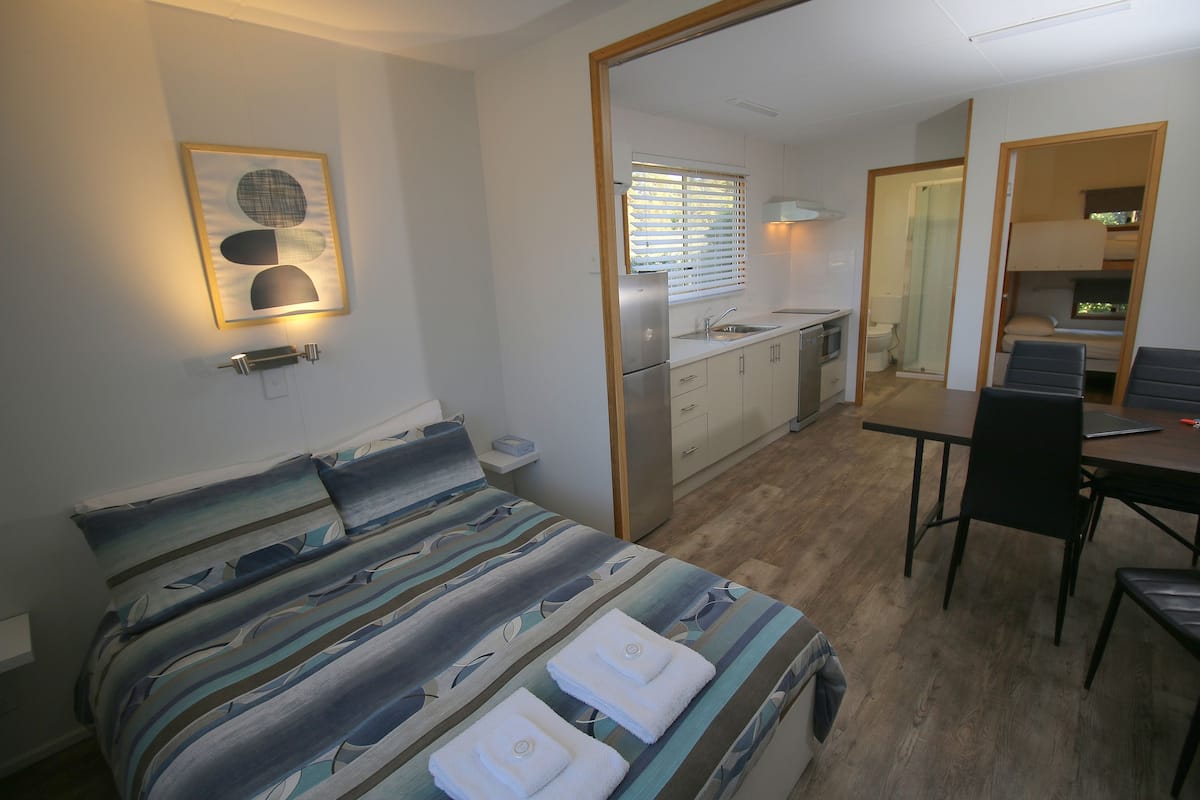 Une pièce de taille modeste comprenant un lit, une petite kitchenette, un coin repas et une salle de bain.