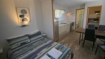 A compact room with a bed, a small kitchenette, a dining area, and a bathroom.