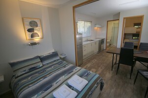 Habitación compacta con cama, kitchenette pequeña, zona de comedor y baño.
