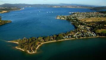 An aerial view of a coastal town with a marina, residential areas, and a forested peninsula.