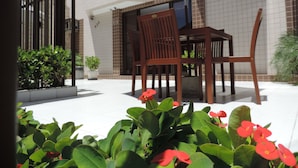 An outdoor patio with a wooden table and chairs, a large umbrella, and potted plants. - Iracema Mar Hotel (Fortaleza)