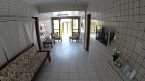 A hotel corridor with a sofa, chairs, a TV, and a kitchen area with a sink and utensils. - Iracema Mar Hotel (Fortaleza)