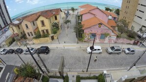 A street view with parked cars, a pedestrian, and buildings with red-tiled roofs. - Iracema Mar Hotel (Fortaleza)