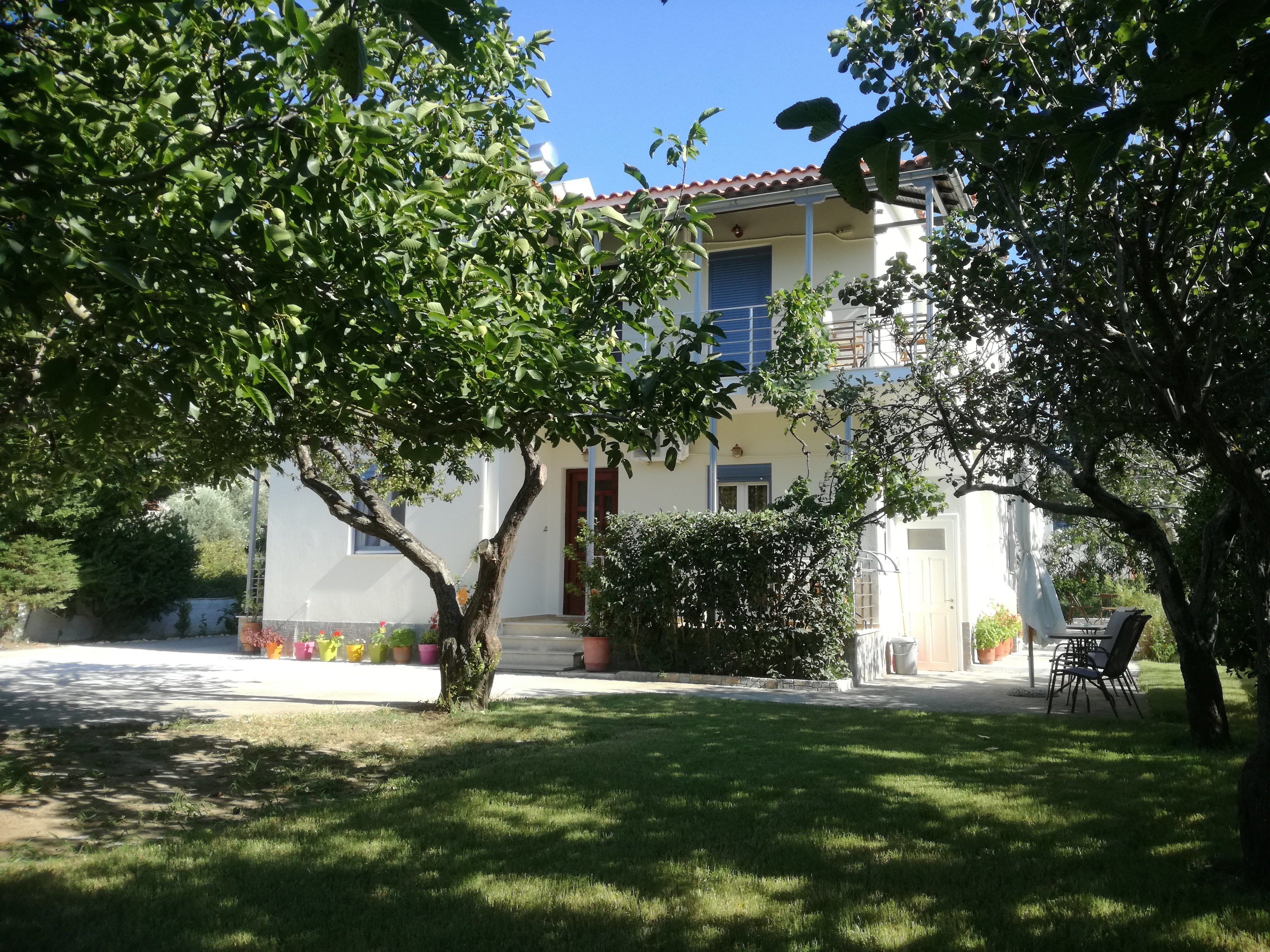 A building with a white facade, a red-tiled roof, and a well-maintained lawn.
