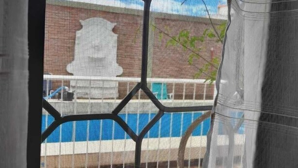 A window with a geometric metal screen, a view of a building, and a clear sky. - Hotel Boutique Bruno Sebástian (Salta)
