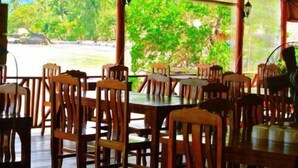 Un restaurant amb caires i taules de fusta, grans finestres i vista a zones verdes a l'exterior.