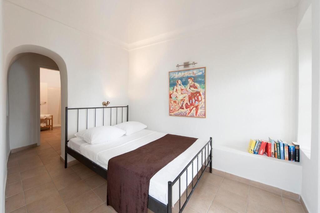 A bedroom with a bed, a painting, and a bookshelf.