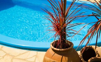 Una piscina al aire libre, sombrillas, sillones reclinables de piscina