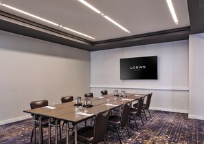 A conference room with a long table, chairs, a flat-screen TV, and a carpeted floor. - Loews Chicago Hotel (Chicago)