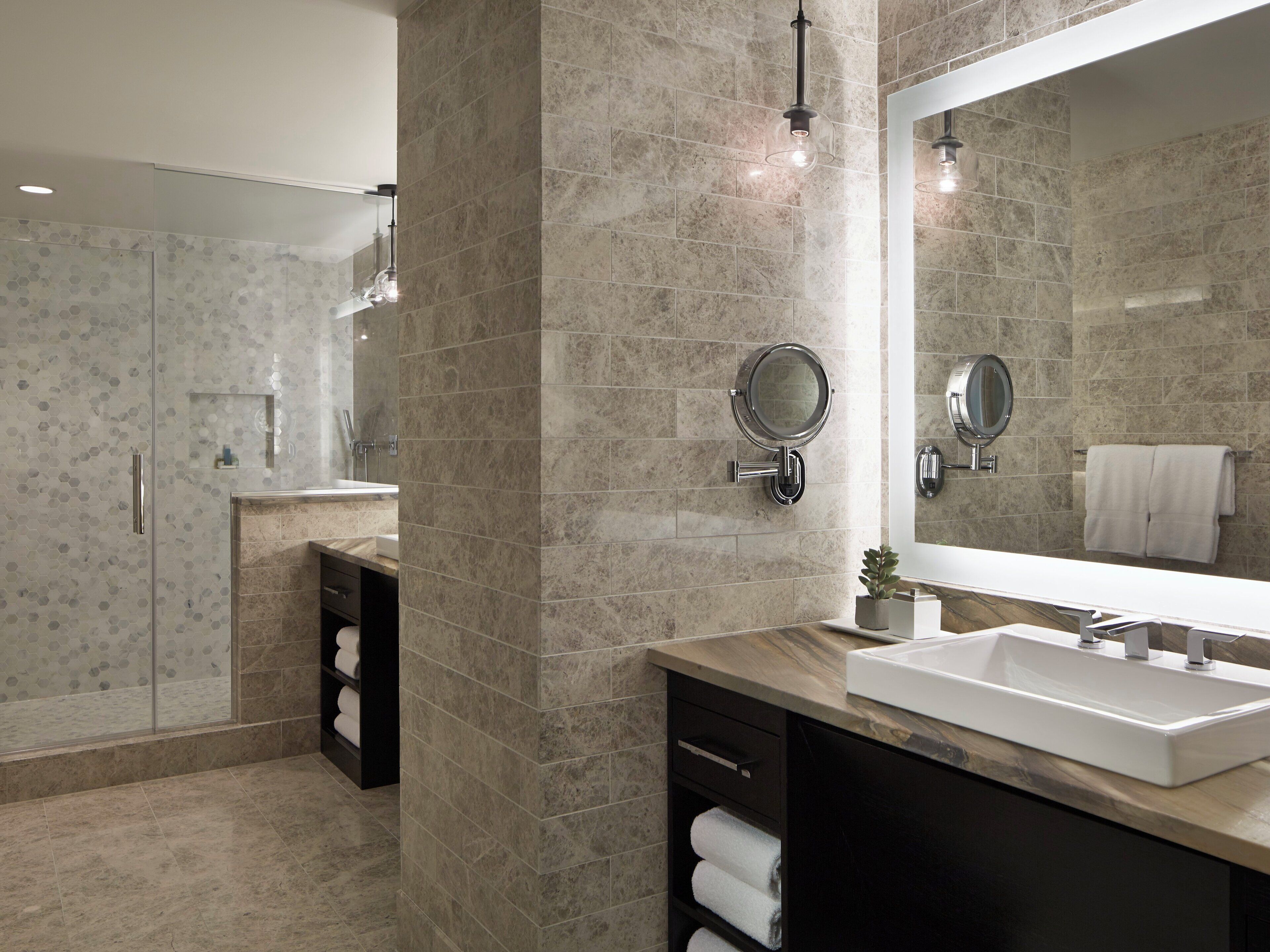 A modern bathroom with a large mirror, a sink, and a towel rack.