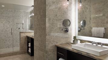 A modern bathroom with a large mirror, a sink, and a towel rack.