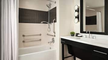 Een moderne badkamer met een bad, douche, wastafel met spiegel en een wasbak.