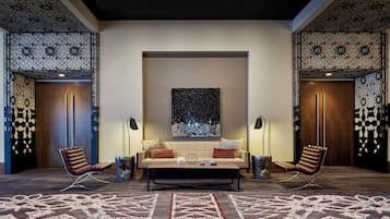 Un área de descanso moderna con un sofá, dos sillones, una mesita de centro y una alfombra estampada.