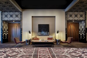 A modern lounge area with a sofa, two armchairs, a coffee table, and a patterned carpet. - Loews Chicago Hotel (Chicago)