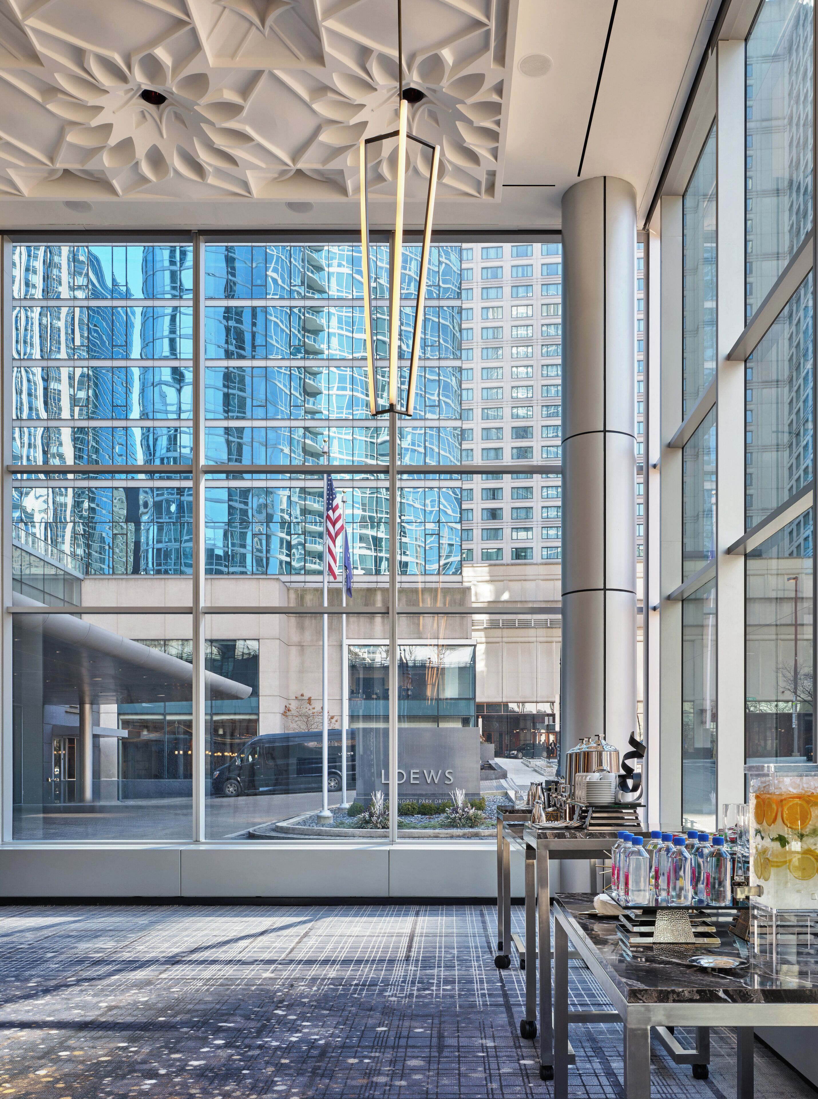A modern hotel lobby with large windows, a flag, and a coffee station.