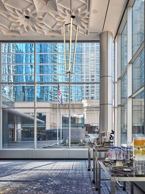 A modern hotel lobby with large windows, a flag, and a coffee station. - Loews Chicago Hotel (Chicago)