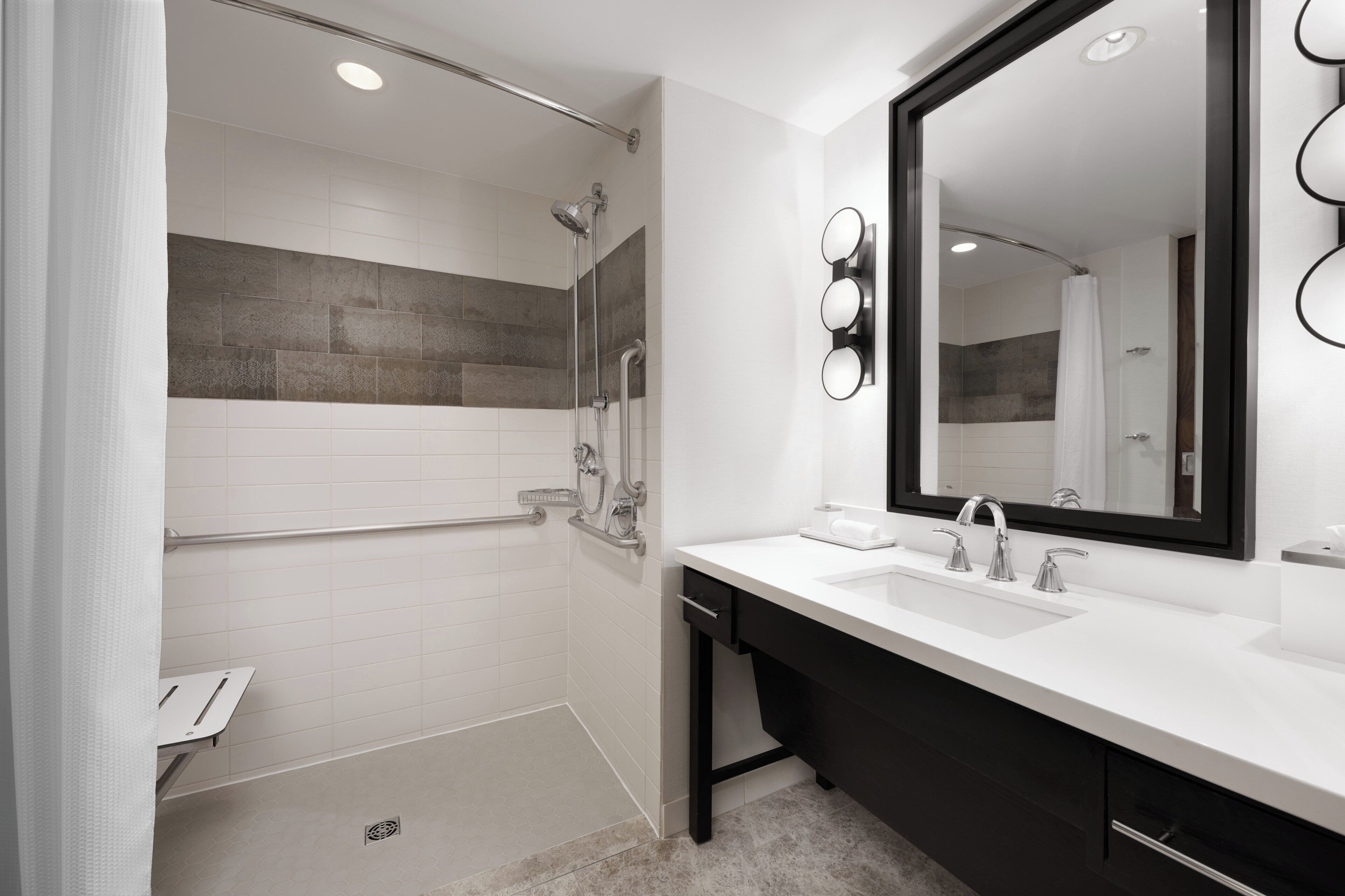 A modern bathroom with a walk-in shower, a large mirror, and a white sink.