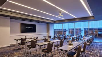 A conference room with a large screen displaying "LOEWS HOTEL" and a long table with chairs.