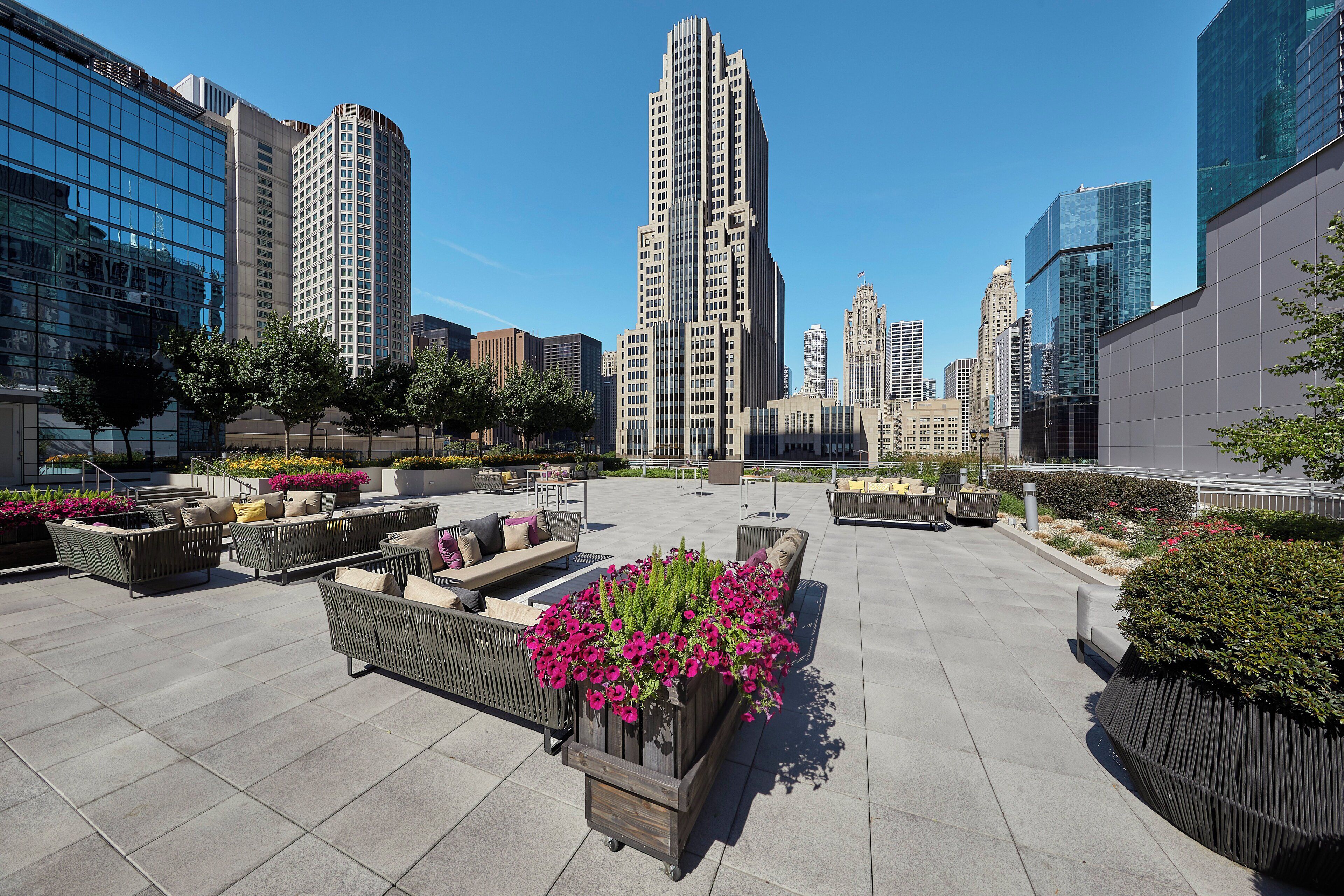 A rooftop terrace with outdoor seating and flower planters.