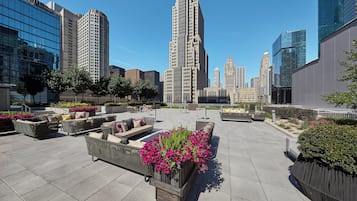 A rooftop terrace with outdoor seating and flower planters.