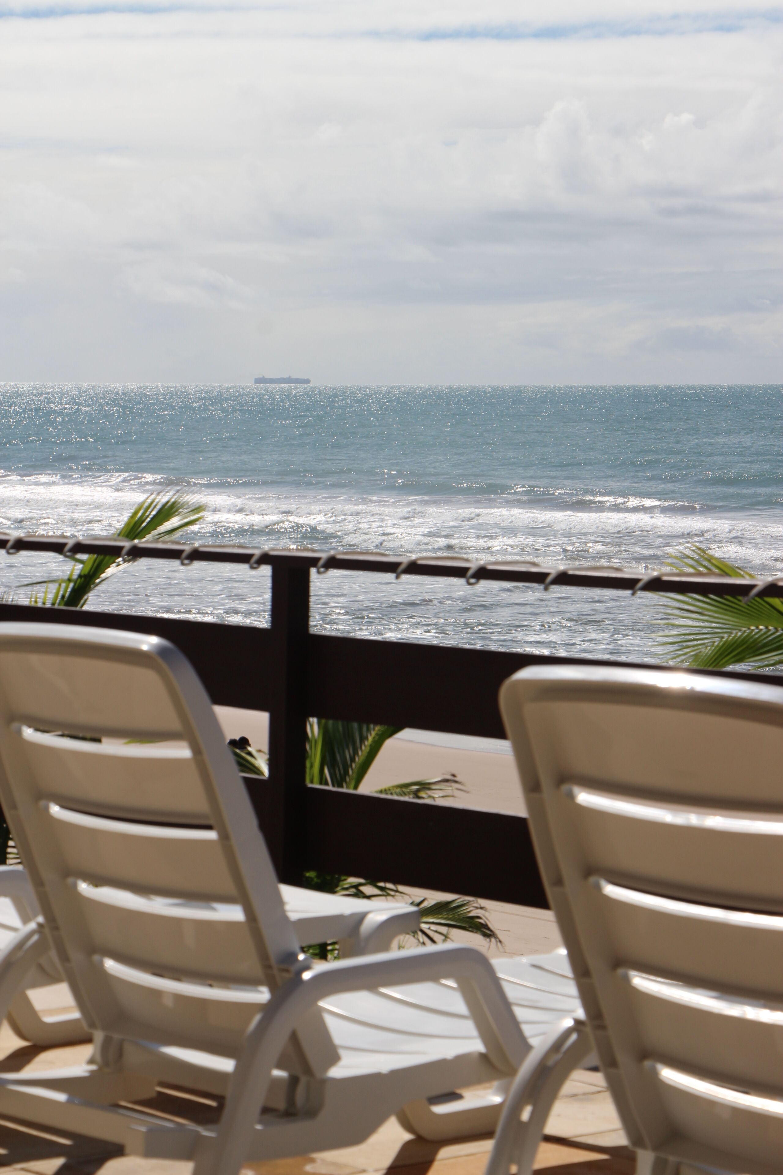 Na praia, espreguiçadeiras, guarda-sóis, toalhas de praia 