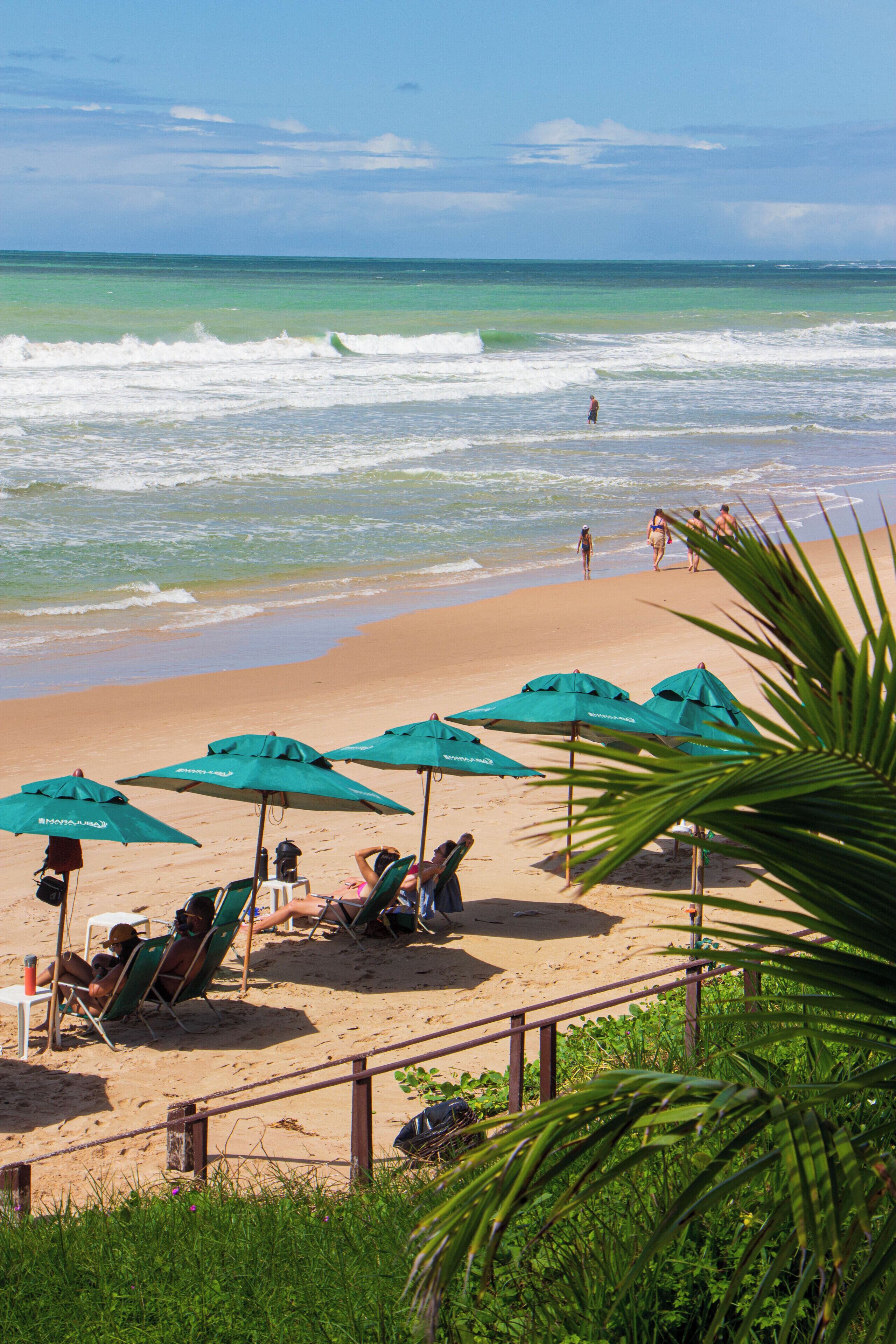 Na praia, espreguiçadeiras, guarda-sóis, toalhas de praia 