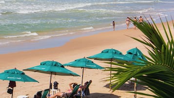 Na praia, espreguiçadeiras, guarda-sóis, toalhas de praia